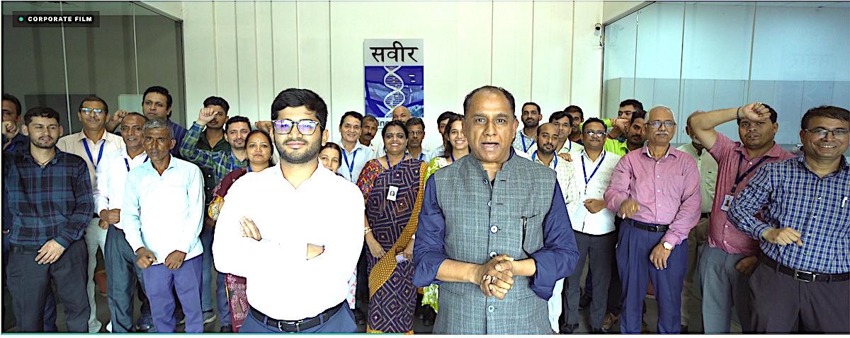 Saveer team gathered together at the company office beneath the Saveer logo